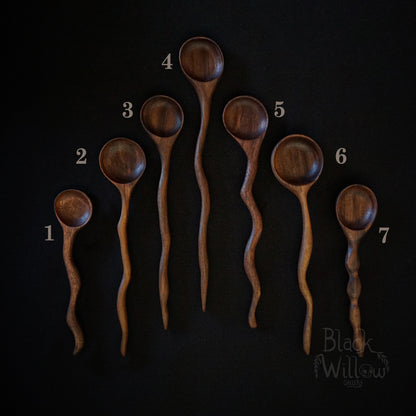 Seven different wooden spoons and displayed on a black background, numbered 1 through 7. The spoons have a warm medium-brown wood finish with visible grain patterns.